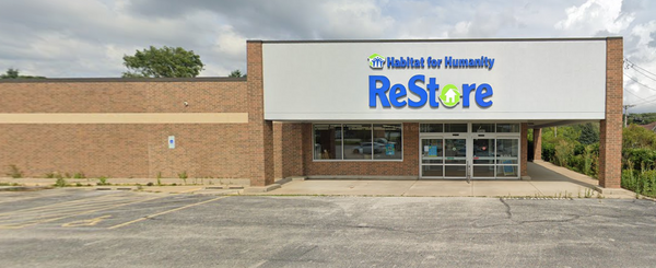 Oak Forest Habitat for Humanity ReStore storefront with brick facade, automatic sliding double doors, and a large, blue and green "Habitat for Humanity ReStore" sign.