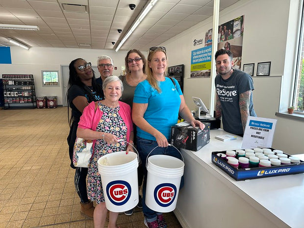 Group of people in Oak Forest ReStore with buckets labeled 'Cubs' and Habitat ReStore t-shirts