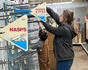 Person and child in a hardware store aisle with signs indicating types of fasteners.