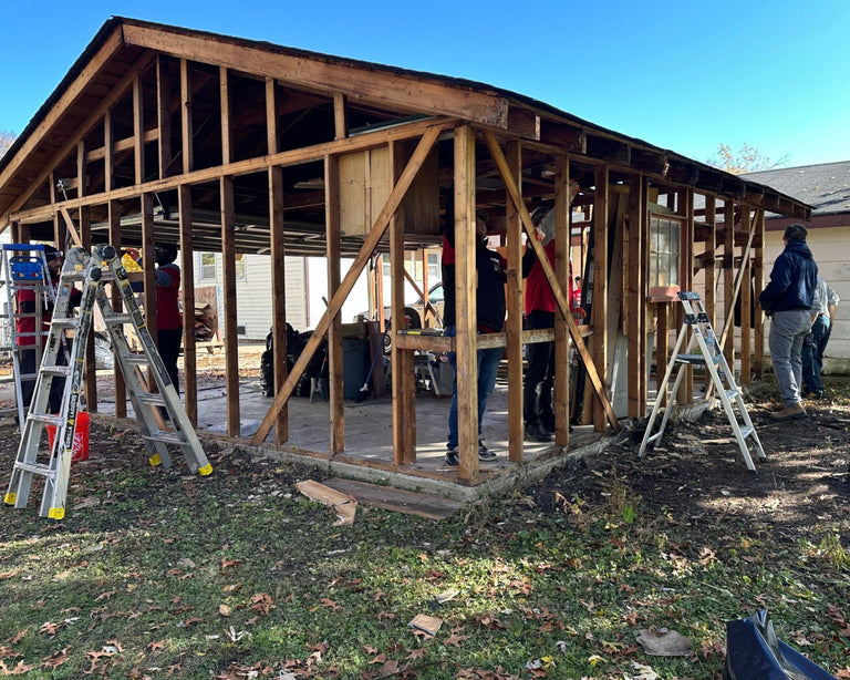 Wooden structure under construction with people working on a clear day.